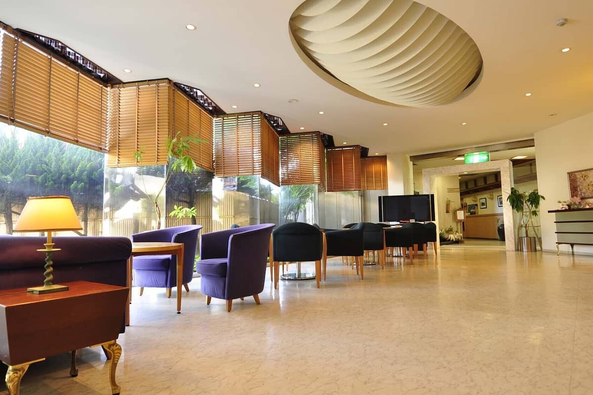 Eine Hotelhalle mit Sitzgelegenheiten, einer Rezeption und einem Fernseher.