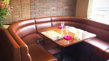 A restaurant booth with a wooden table set for two, including cutlery and a glass.
