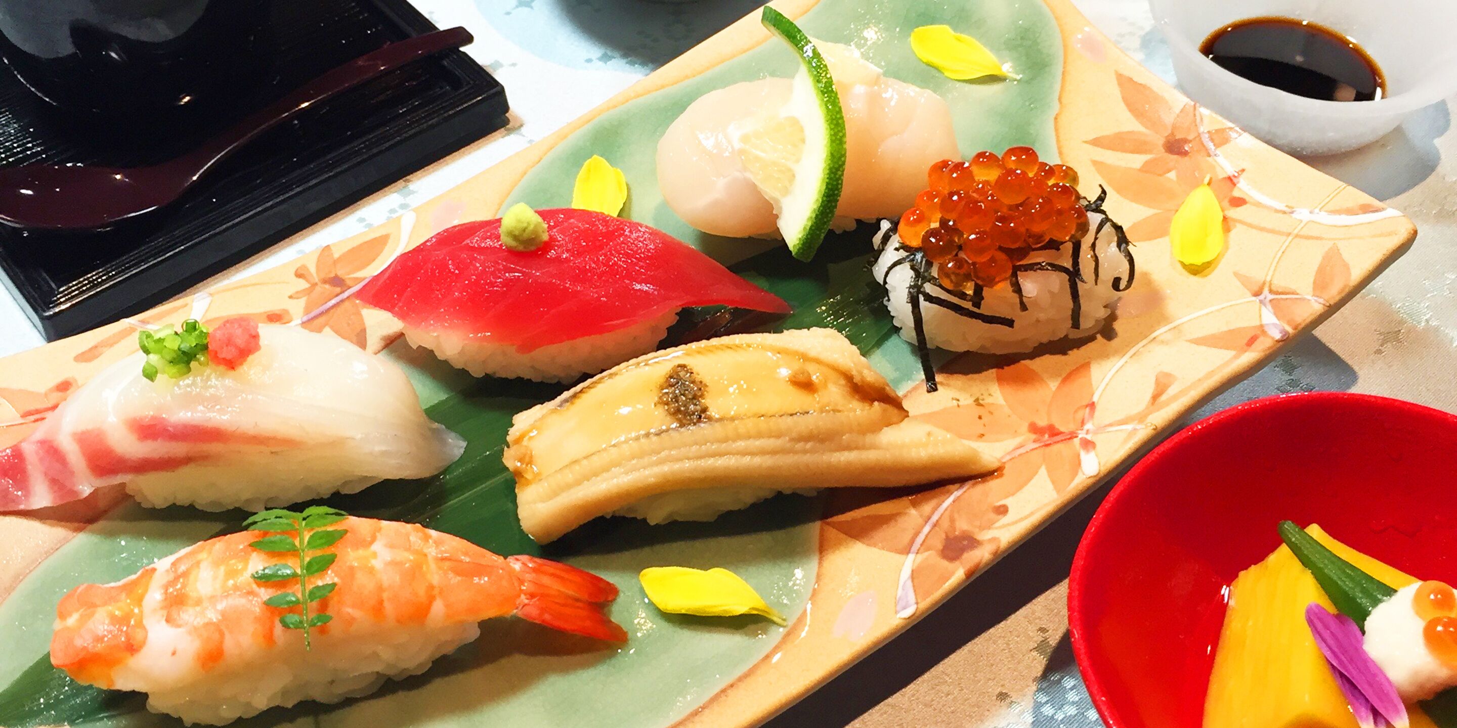 Variedad de piezas de sushi en un plato, acompañadas de salsa de soja.