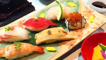 Variedad de piezas de sushi en un plato, acompañadas de salsa de soja.