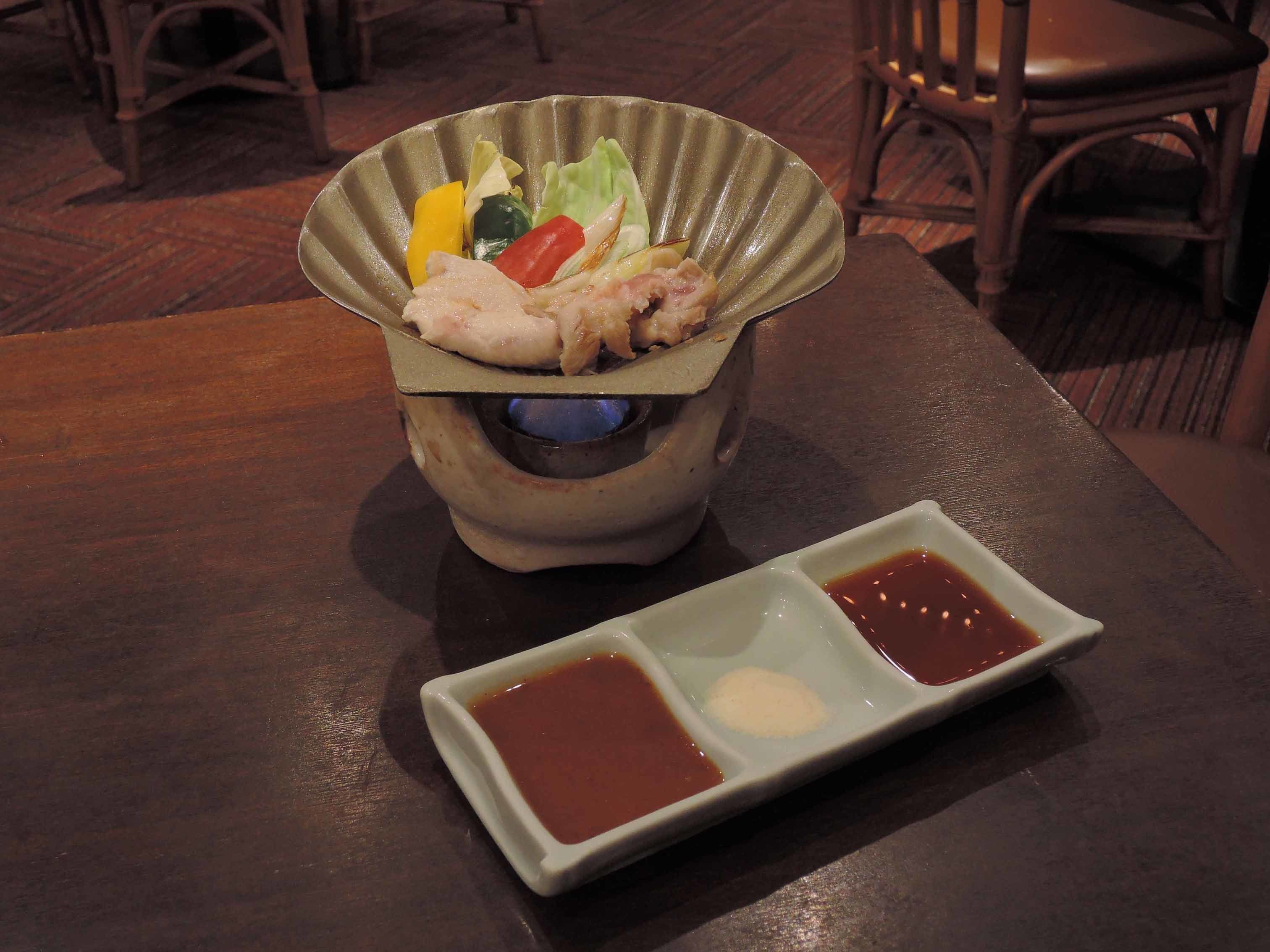 A traditional Japanese meal with a bowl of sashimi and two small dishes of soy sauce and wasabi.