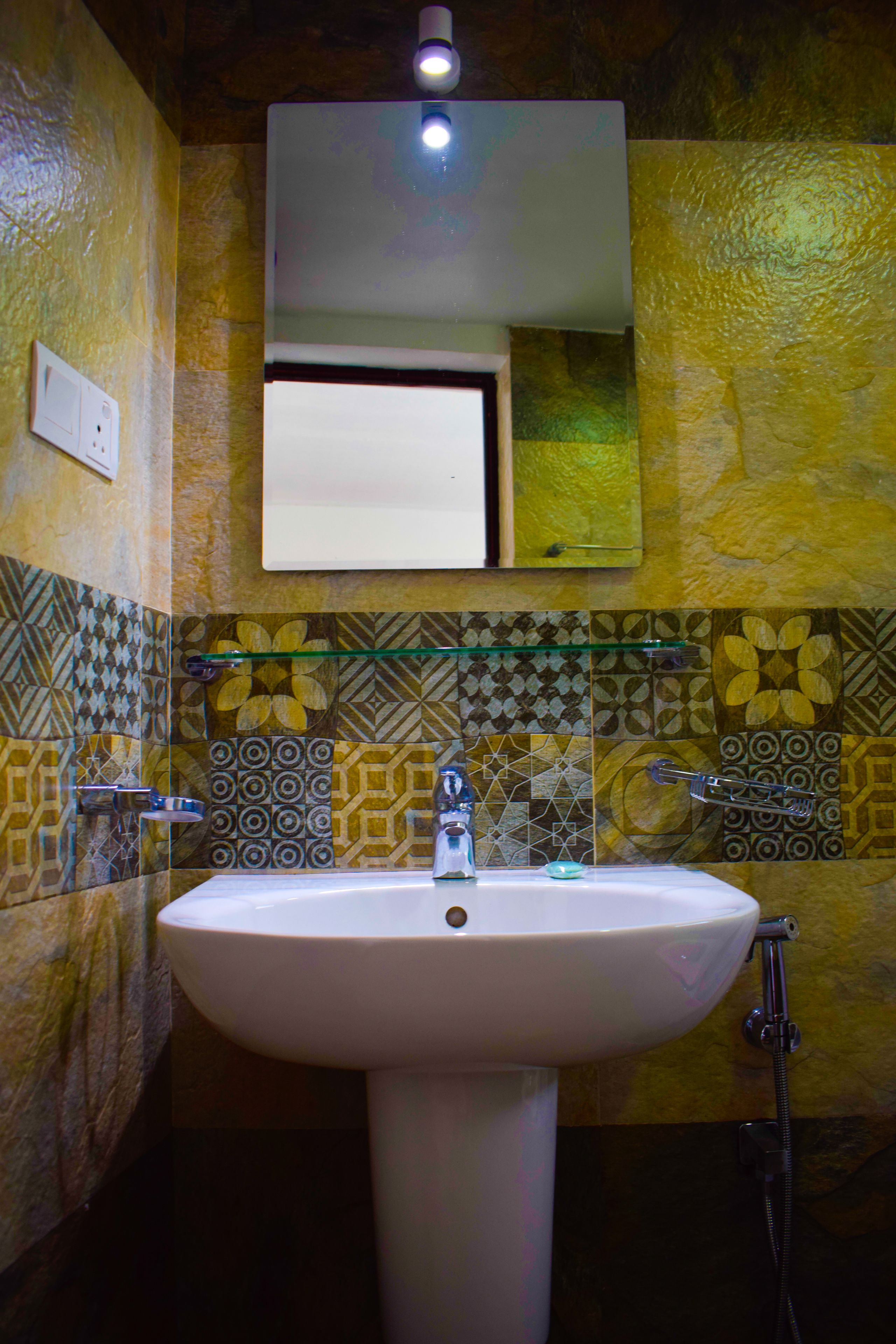 A bathroom with a white sink, a mirror above it, and patterned tiles on the walls.