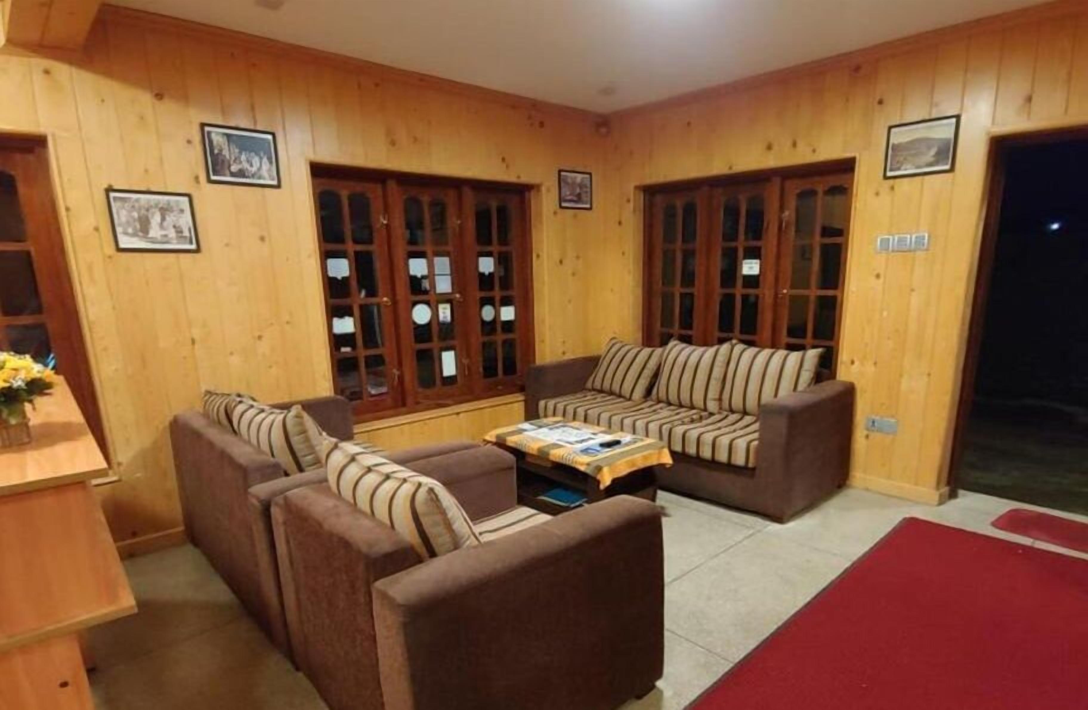 A cozy room with wooden walls, two sofas, a small table, and a red rug.