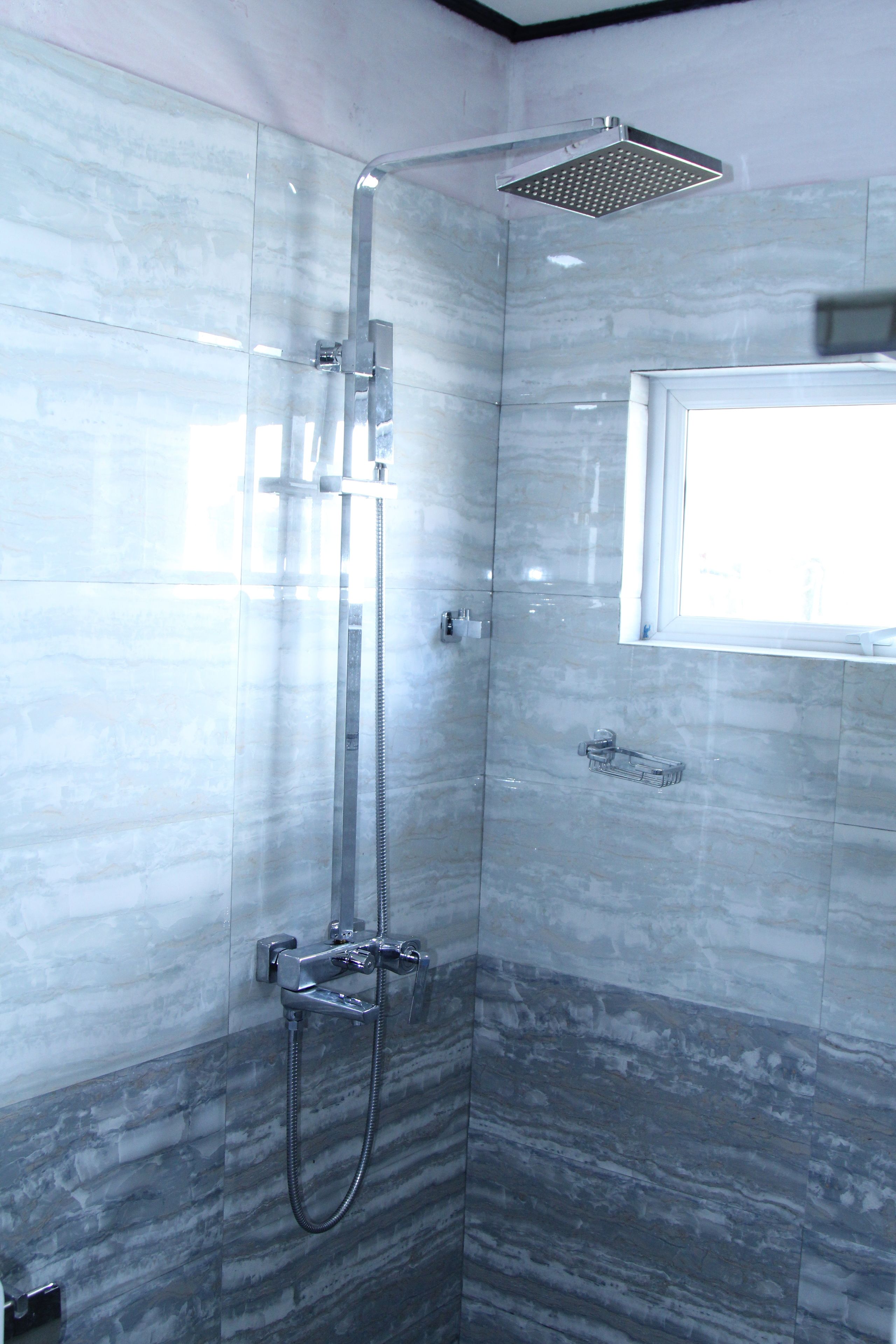 A modern shower with a handheld showerhead and a fixed overhead showerhead.