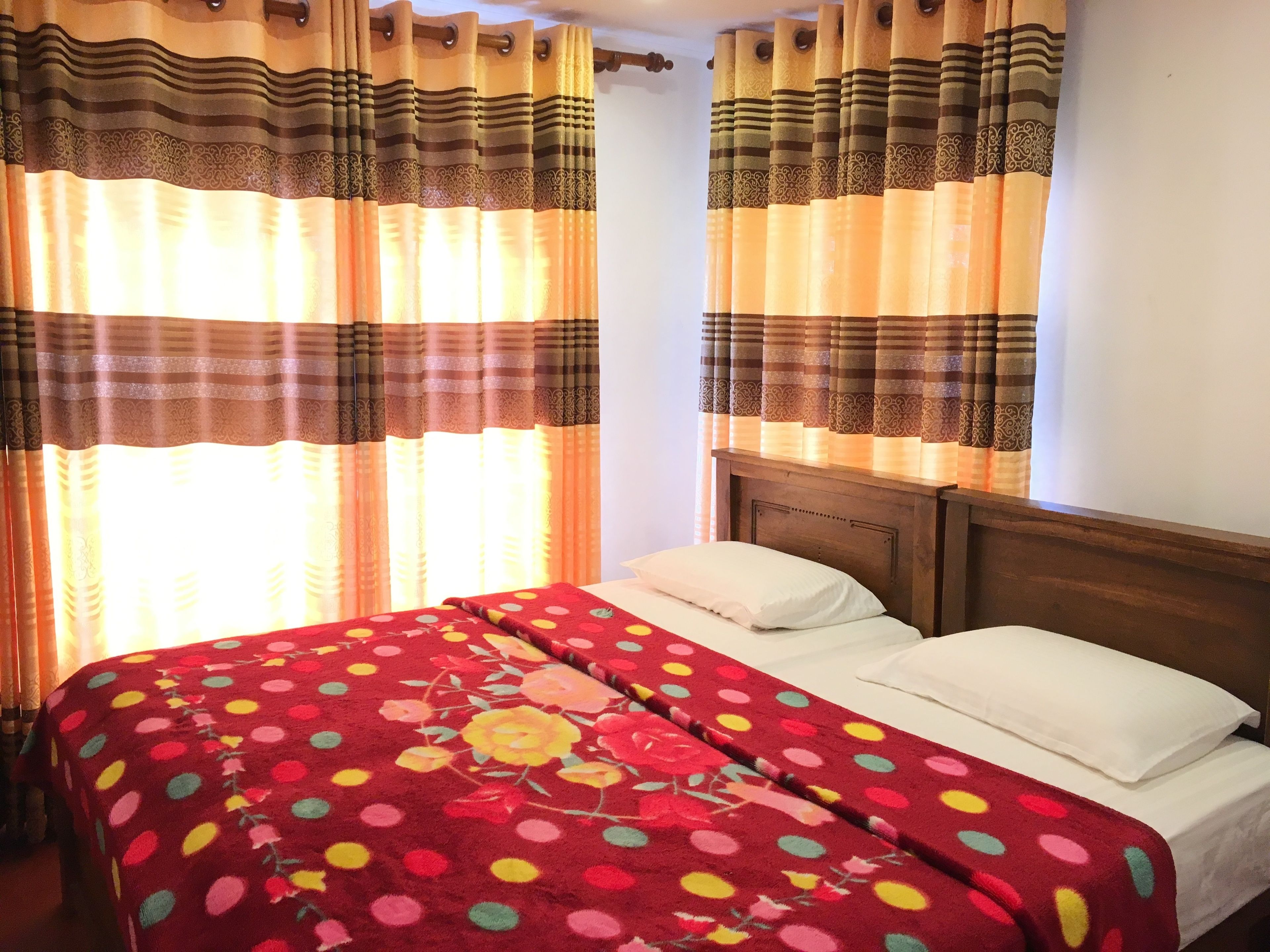 Un dormitorio con cama, cortinas y cabecera de madera.