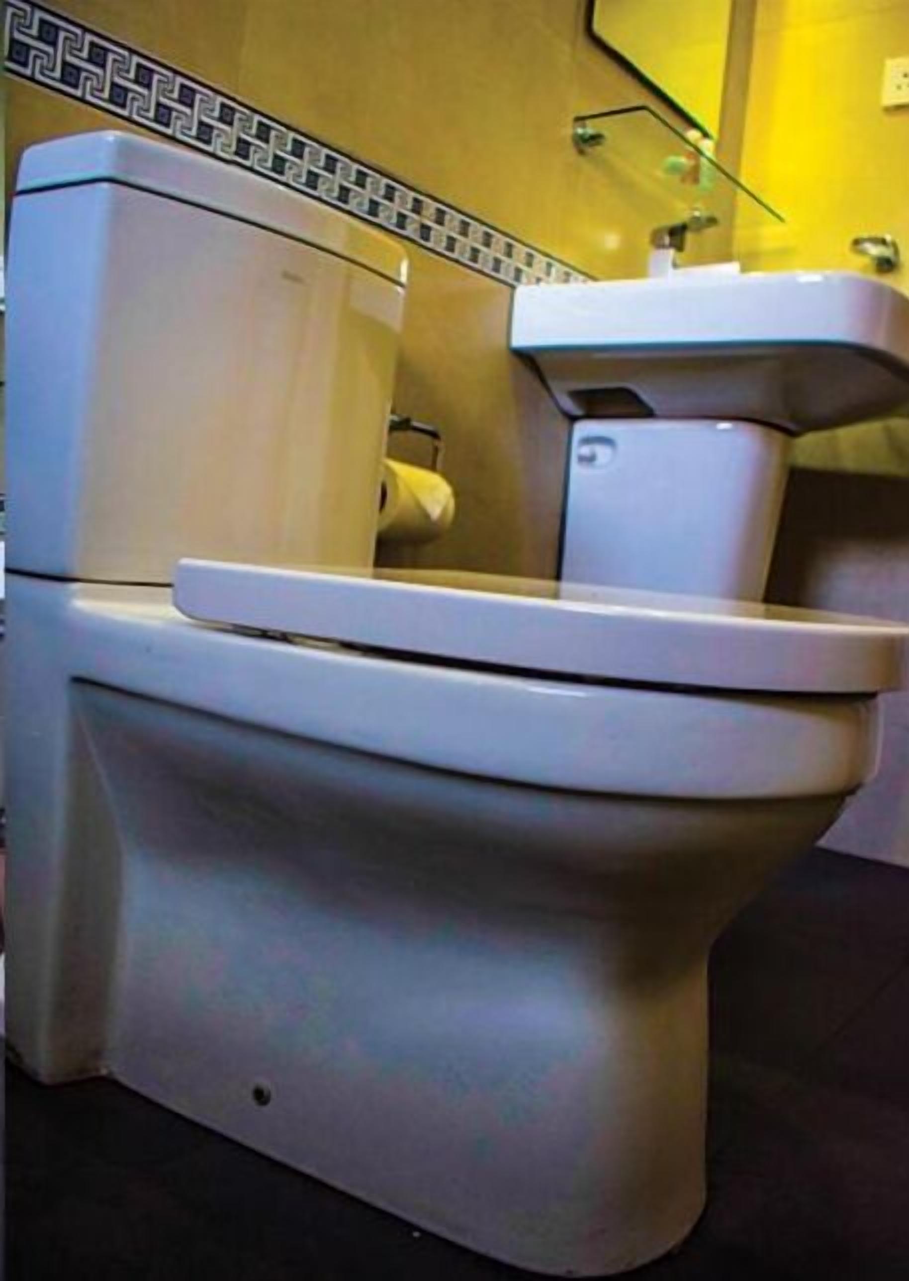 A toilet with a white tank and seat, a visible toilet paper holder, and a tiled backsplash.