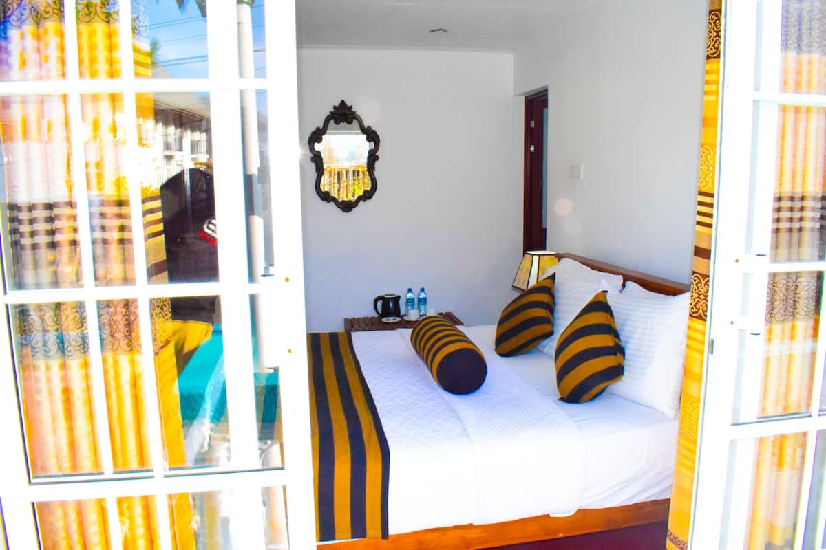 A bed with striped pillows, a bedside table with a lamp, and a mirror on the wall.