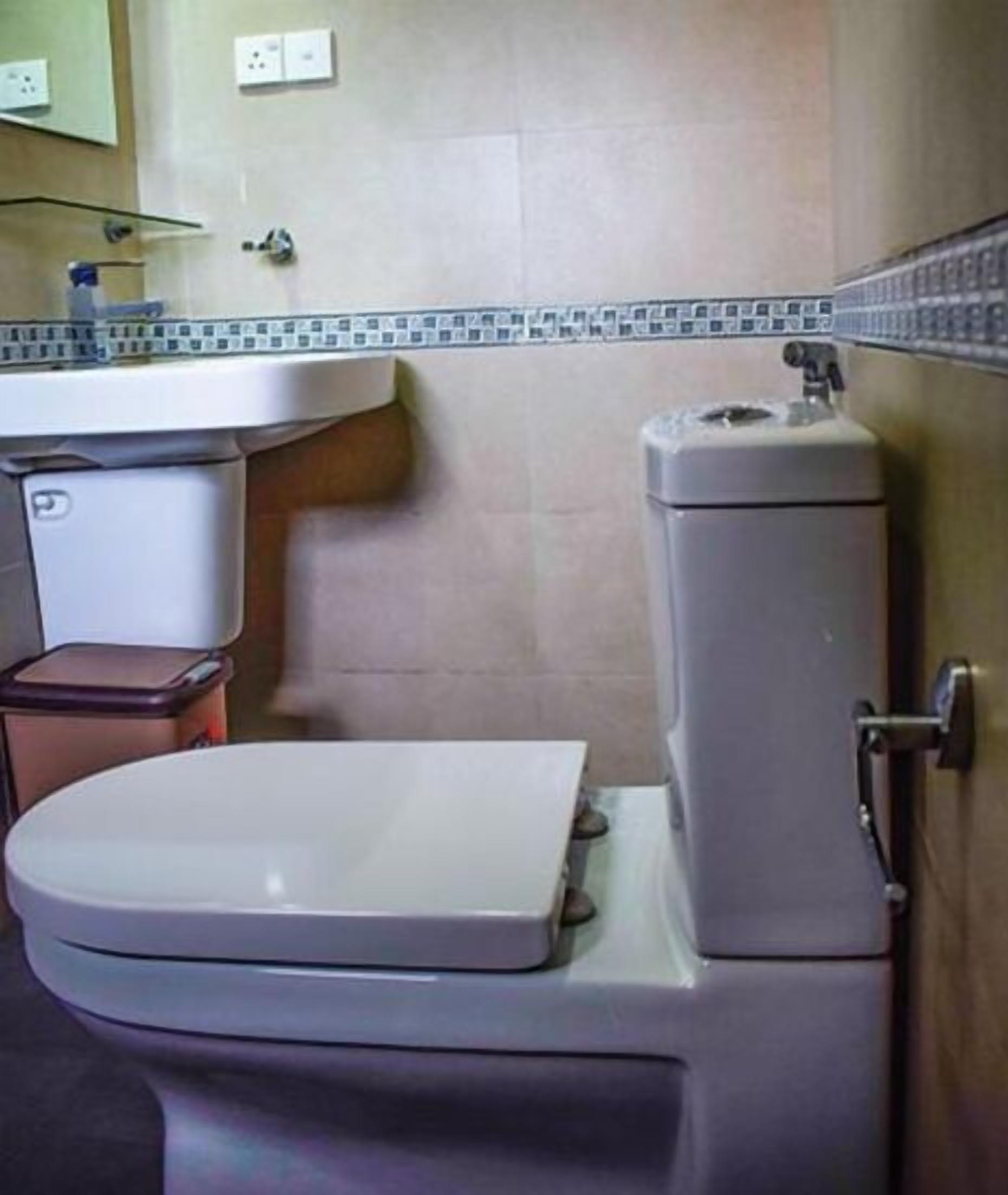 A bathroom with a toilet, a sink, and a mirror.