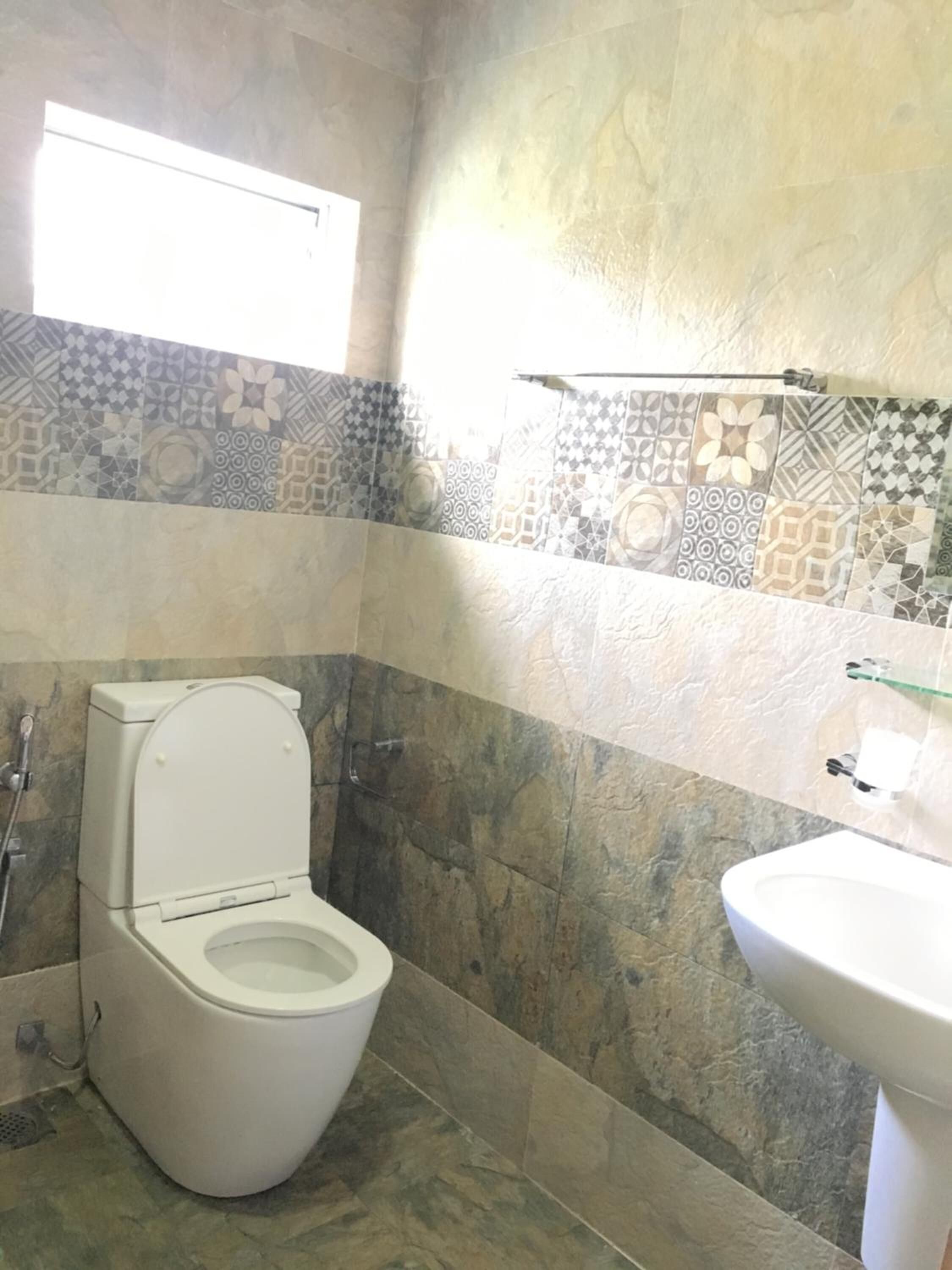 Ein Badezimmer mit Toilette, Waschbecken und Fliesen mit Muster.