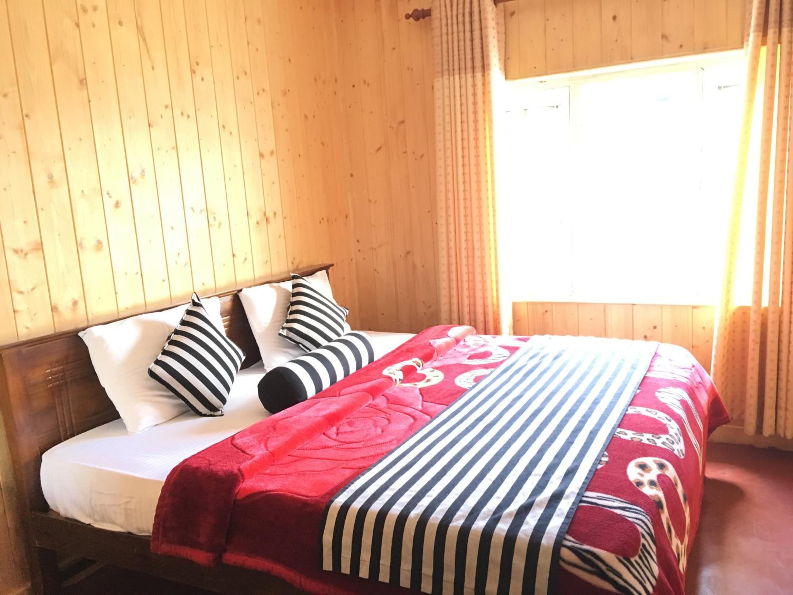 Una habitación de madera con una cama, cortinas y una ventana.