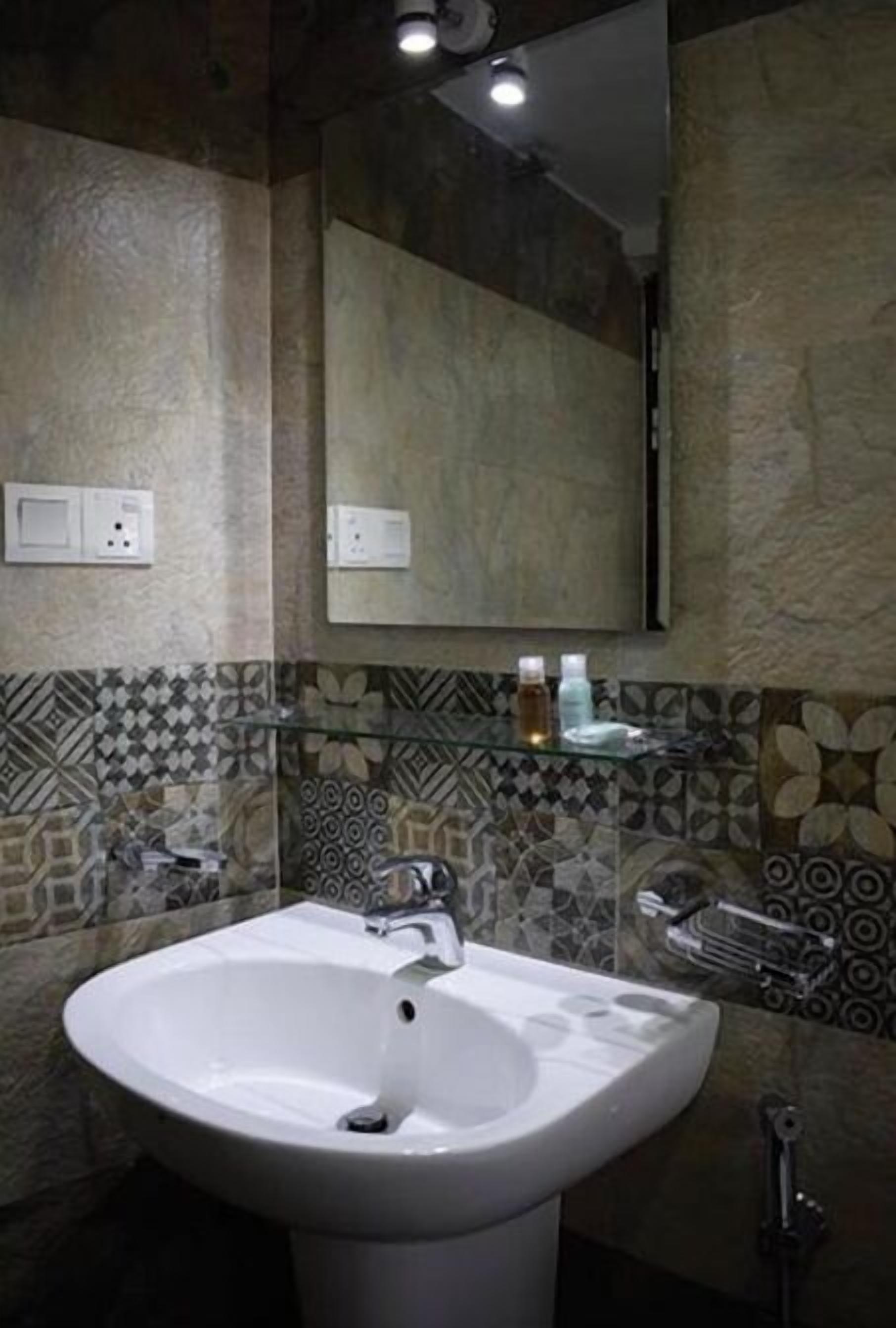 Un bagno con un lavandino bianco di grandi dimensioni, uno specchio e pareti rivestite di piastrelle decorative.