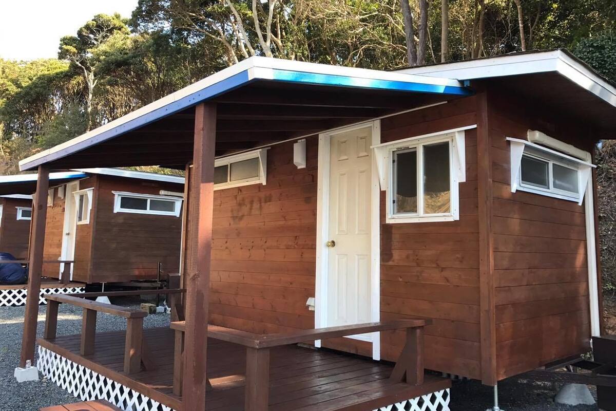 A wooden cabin with a porch, a door, and windows.