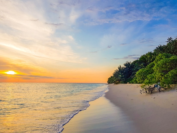 Una playa cerca, arena blanca, sillas reclinables de playa, sombrillas