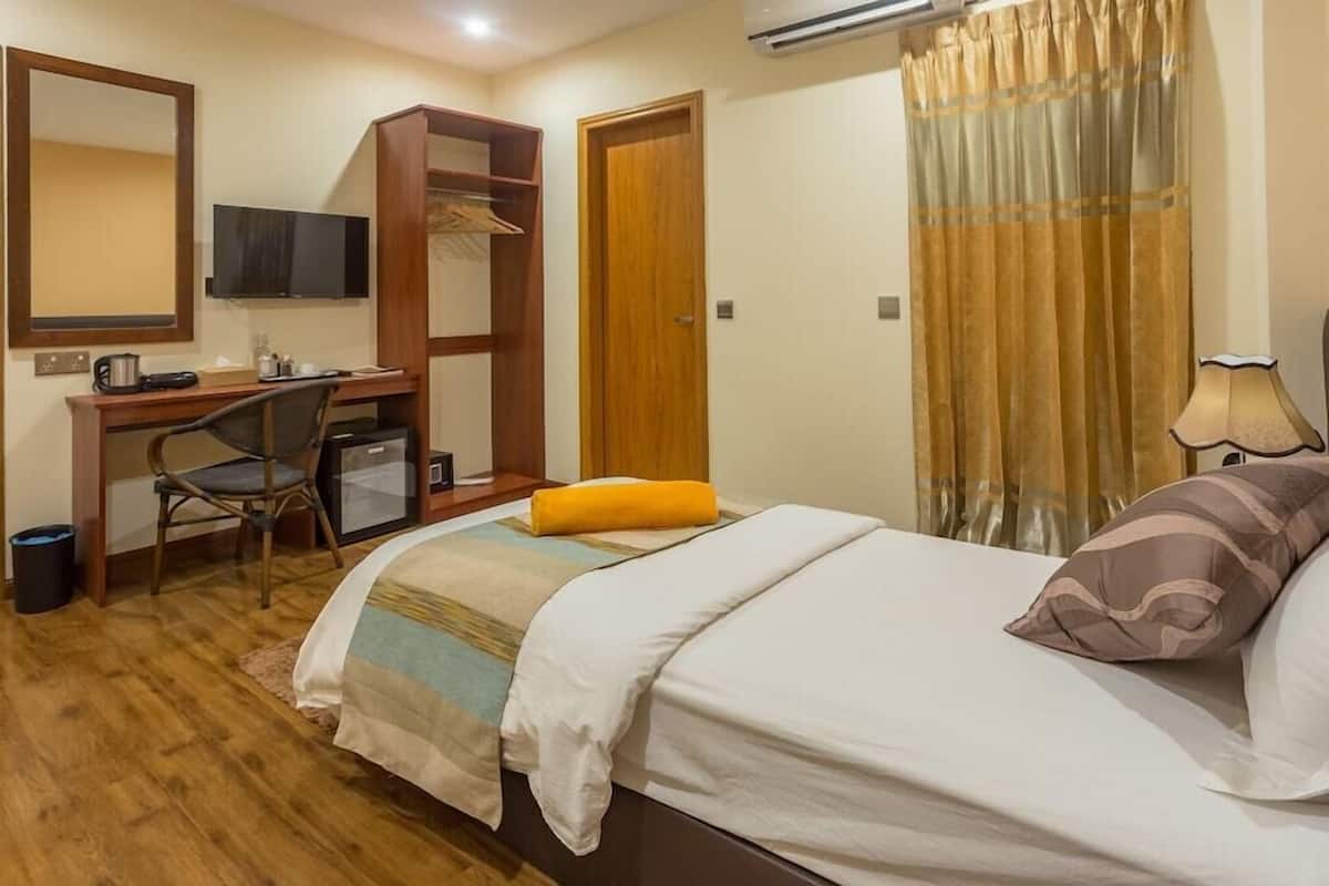Une chambre à coucher comprenant un lit, un bureau avec une chaise, une télévision et une armoire.