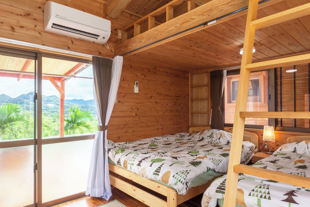 A wooden cabin with a bed, a window with curtains, and an air conditioning unit.