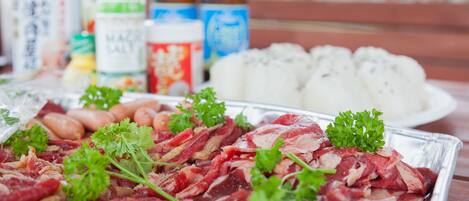 A table with raw meat, vegetables, and condiments.