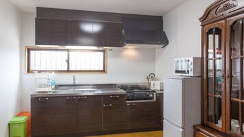 Una cocina con armarios de madera oscura, un lavamanos de acero inoxidable, un microondas y una estufa.