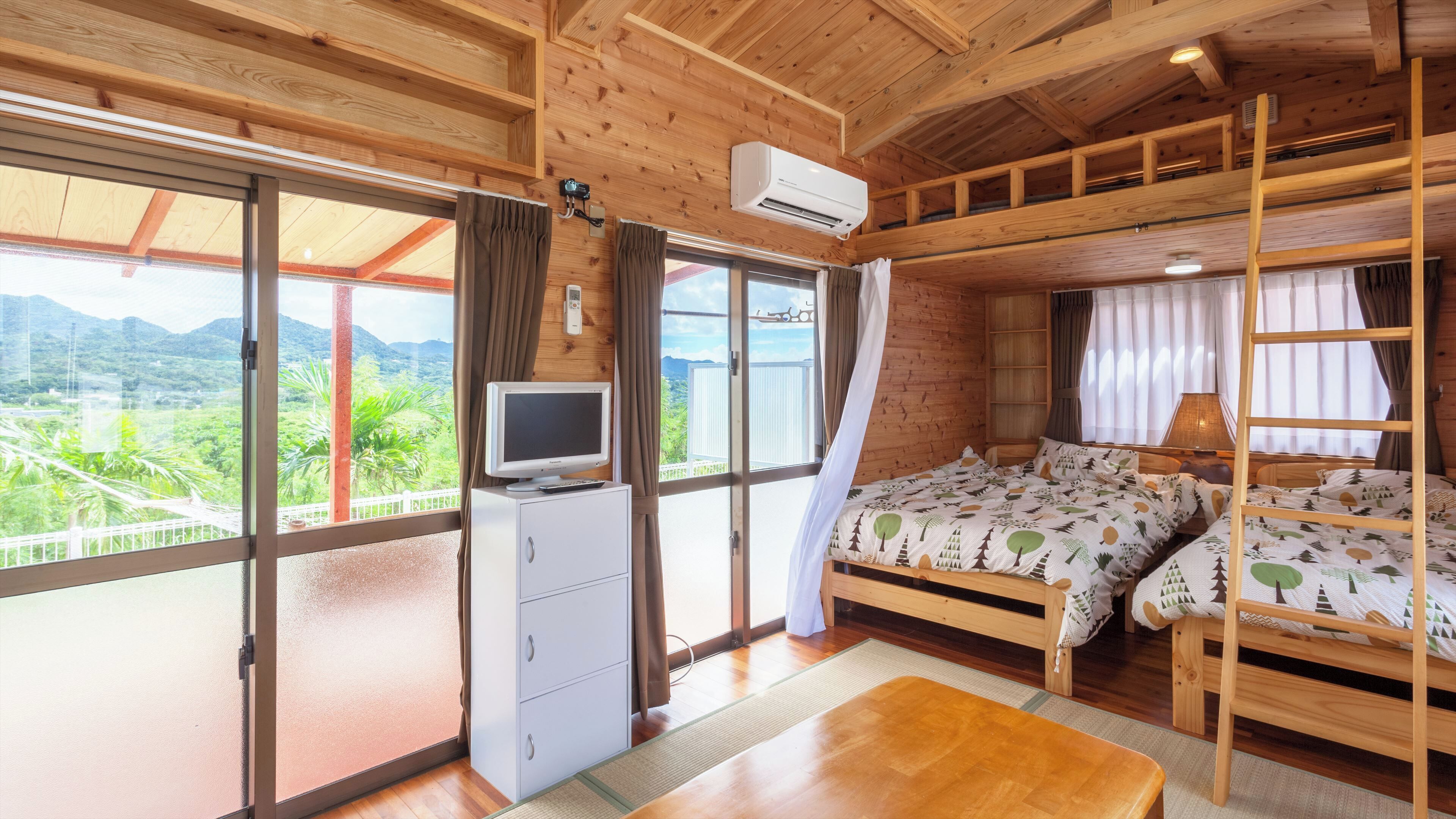 A wooden cabin with a bed, a desk, and a TV.