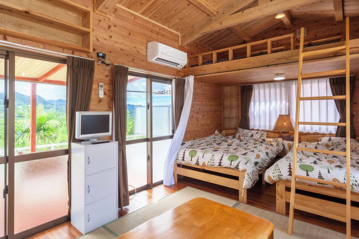 A wooden cabin with a bed, a desk, and a TV.