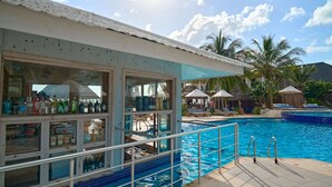 A poolside bar with a view of the pool and palm trees. - Kendwa Rocks Beach Hotel (Kendwa)