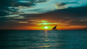 A sunset over the ocean with a sailboat. - Kendwa Rocks Beach Hotel (Kendwa)