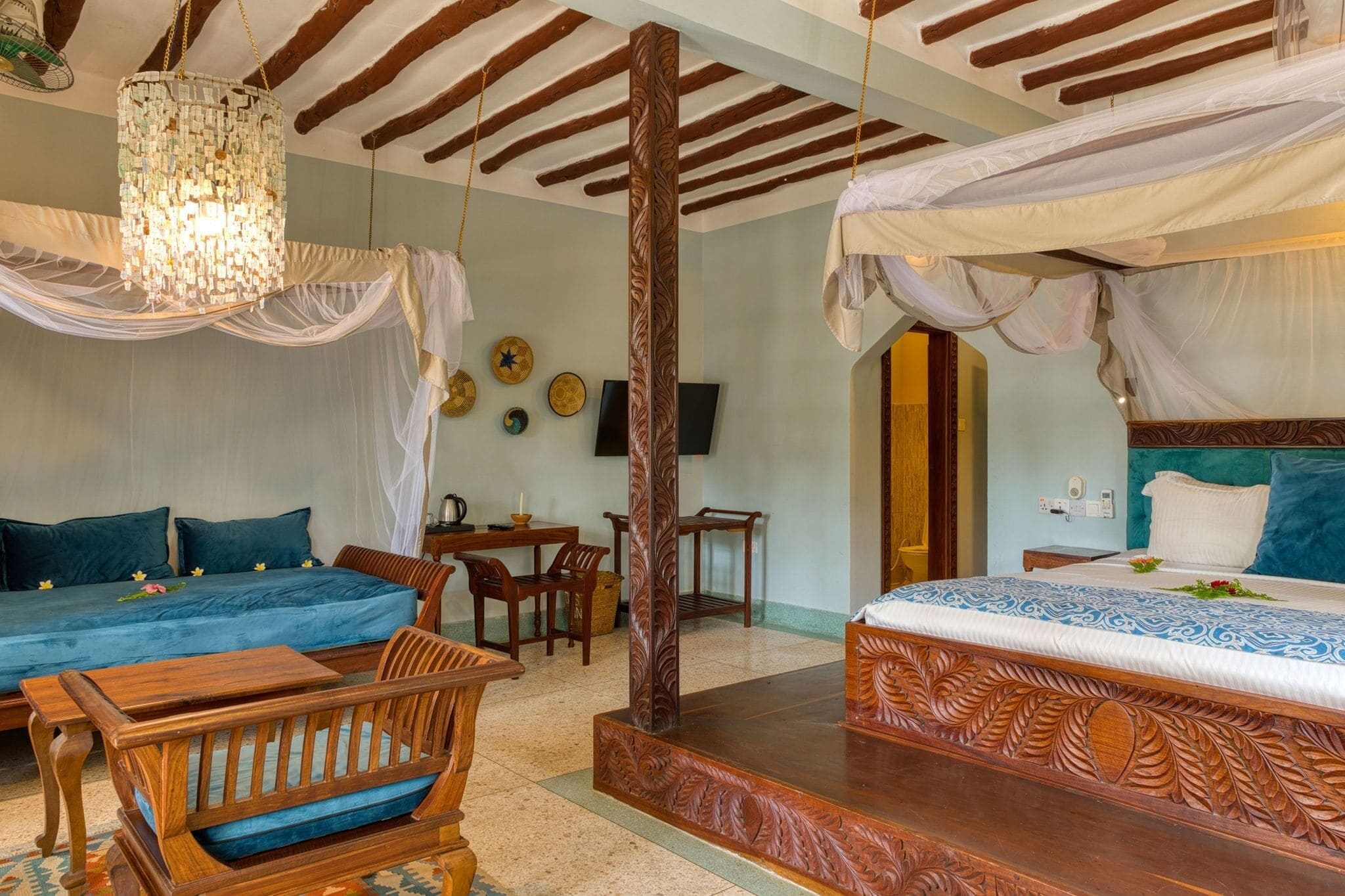 A room with a bed, a sofa, a wooden table, and a hanging chair.