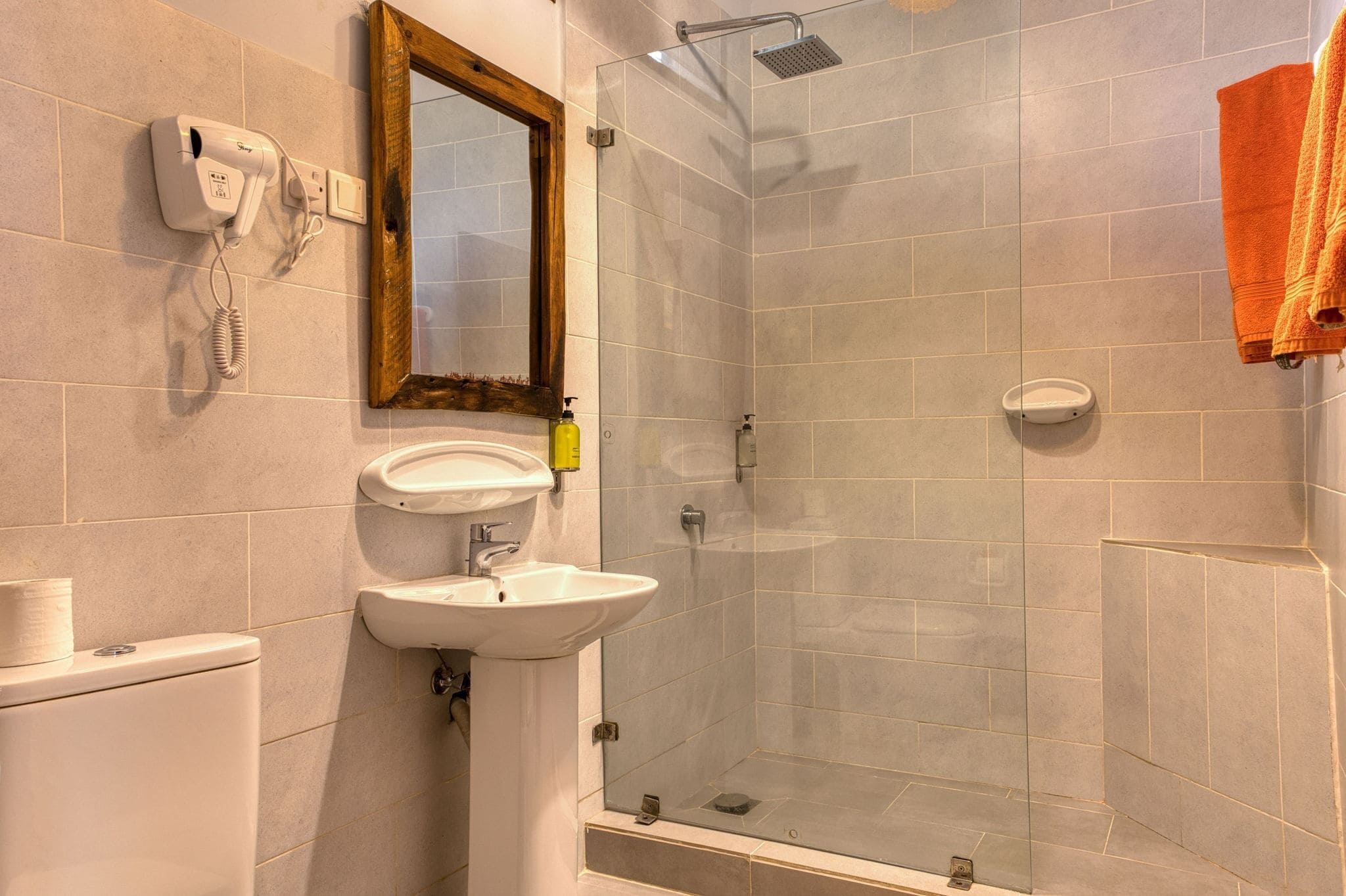 Un baño con inodoro, lavamanos, espejo y ducha.