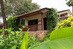 A building with a stone wall, a wooden balcony, and lush greenery. - Kendwa Rocks Beach Hotel (Kendwa)