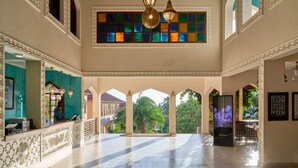 Un hall d’entrée spacieux, doté d’un sol carrelé, d’un comptoir de réception et d’une grande fenêtre aux vitraux colorés.