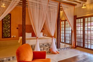 A room with a bed, a chair, and a view through a large window. - Kendwa Rocks Beach Hotel (Kendwa)