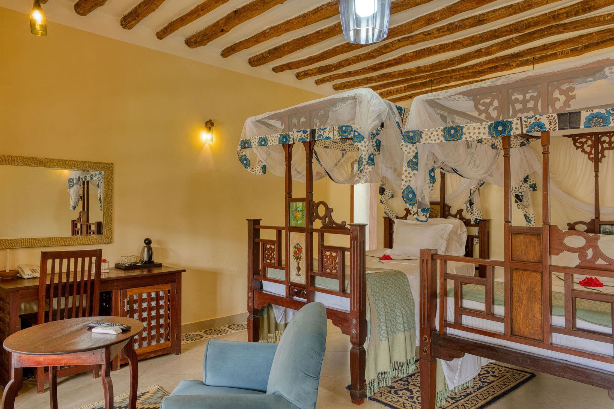 Habitación tradicional con cama, una silla, una mesa y un espejo.