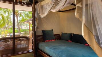 Una habitación con cama, ventana y vista a palmeras.