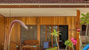 Una casa de madera con techo de tejas, piscina y un área de estar con una silla y una mesa.