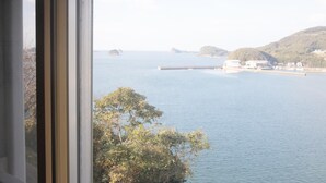A coastal view from a window overlooking calm waters, distant land, and a pier. - Ikijimaso (Iki)