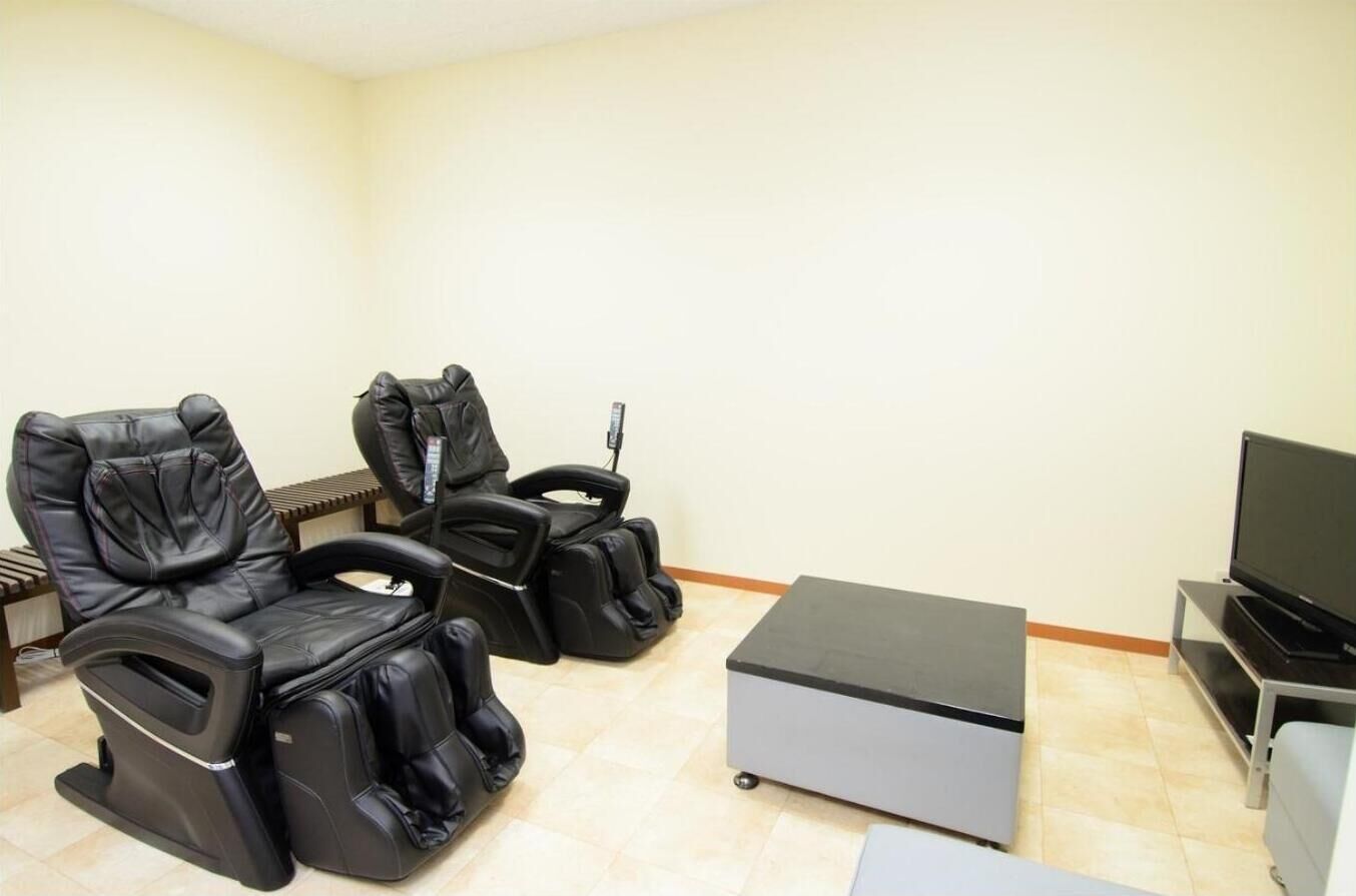 A room with two massage chairs, a small table, and a television.