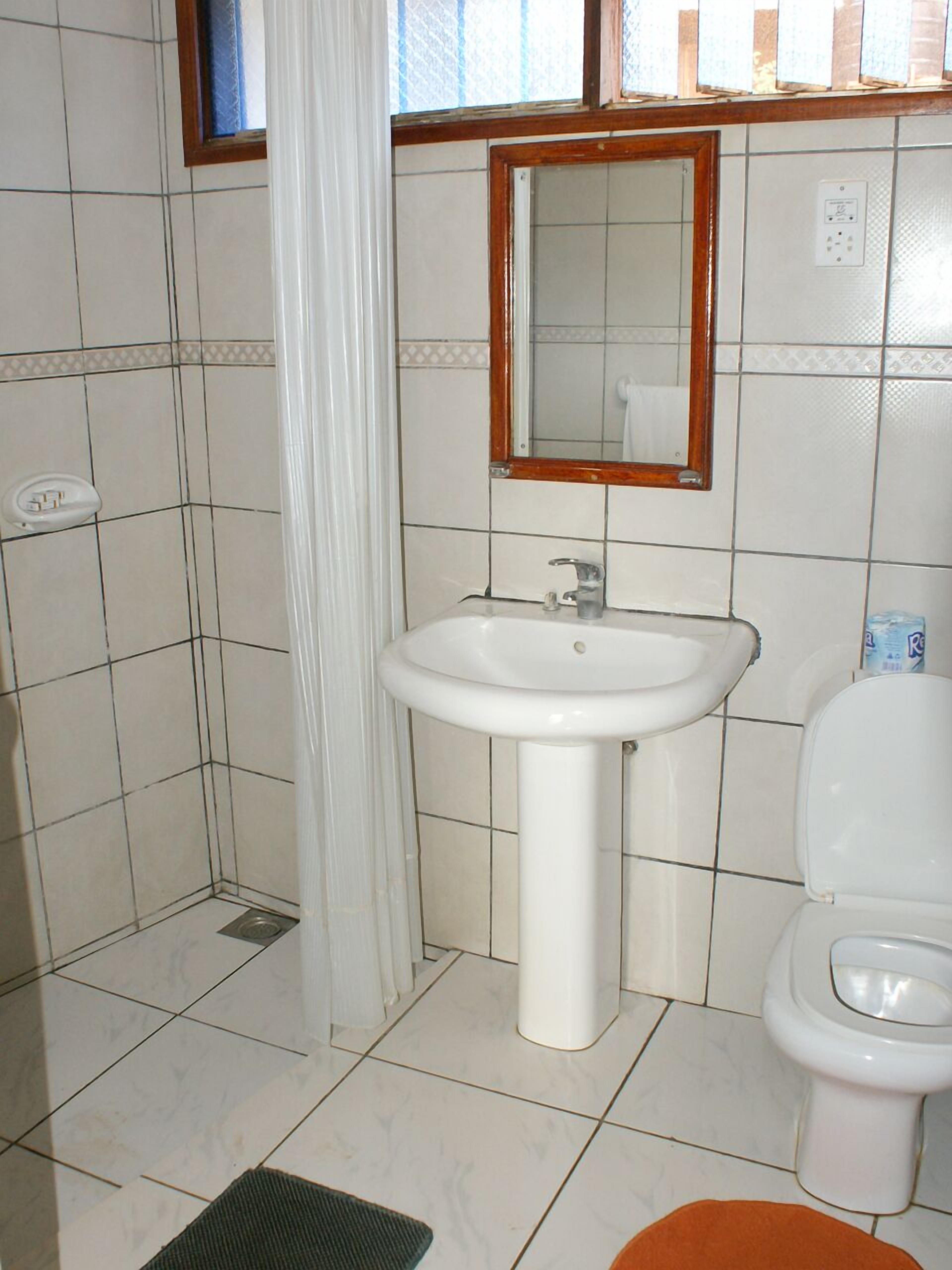 A bathroom with a white sink, a mirror, and a toilet.