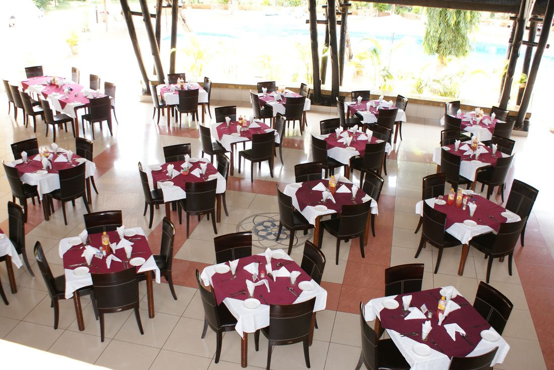 A dining area with tables set for multiple guests, arranged in a circular pattern, with chairs around each table.