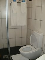 Un baño con inodoro blanco, cabina de ducha y toallero con dos toallas blancas.