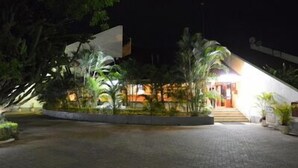 A building with a sloped roof, surrounded by a landscaped area with various plants.