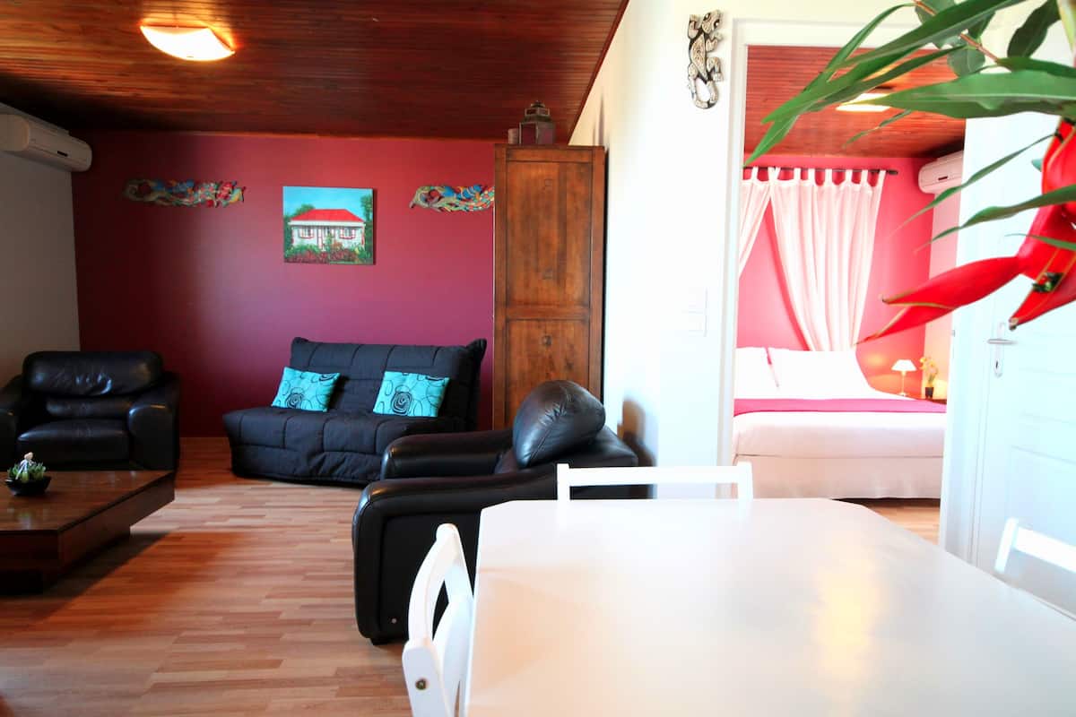 Una sala de estar con un sofá de cuero negro, una mesa blanca y un mueble de madera.