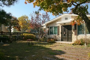 A stone house with a front porch, a small garden, and a wooden fence. - Cindy's B&B (Seoul)