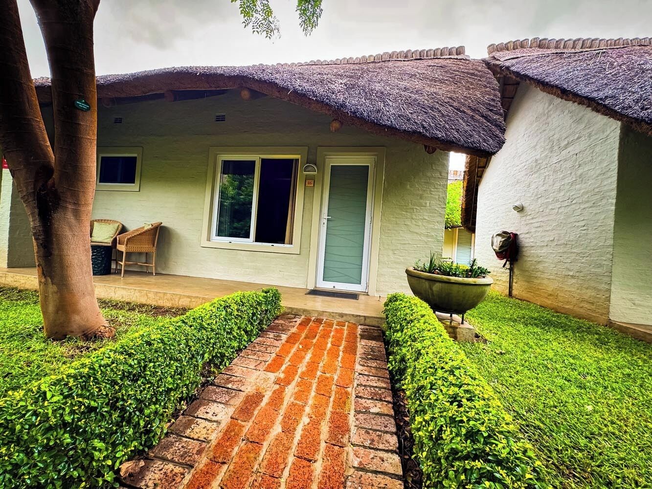 A building with a thatched roof, a paved entrance, and a small porch area.