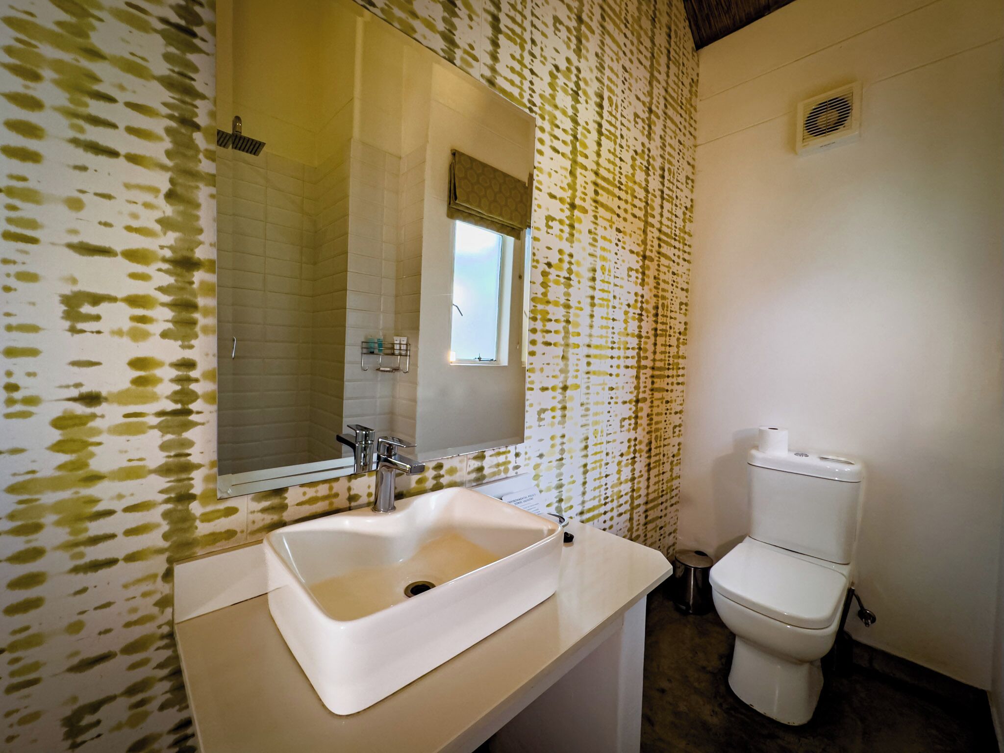 A bathroom with a white sink, mirror, and toilet.
