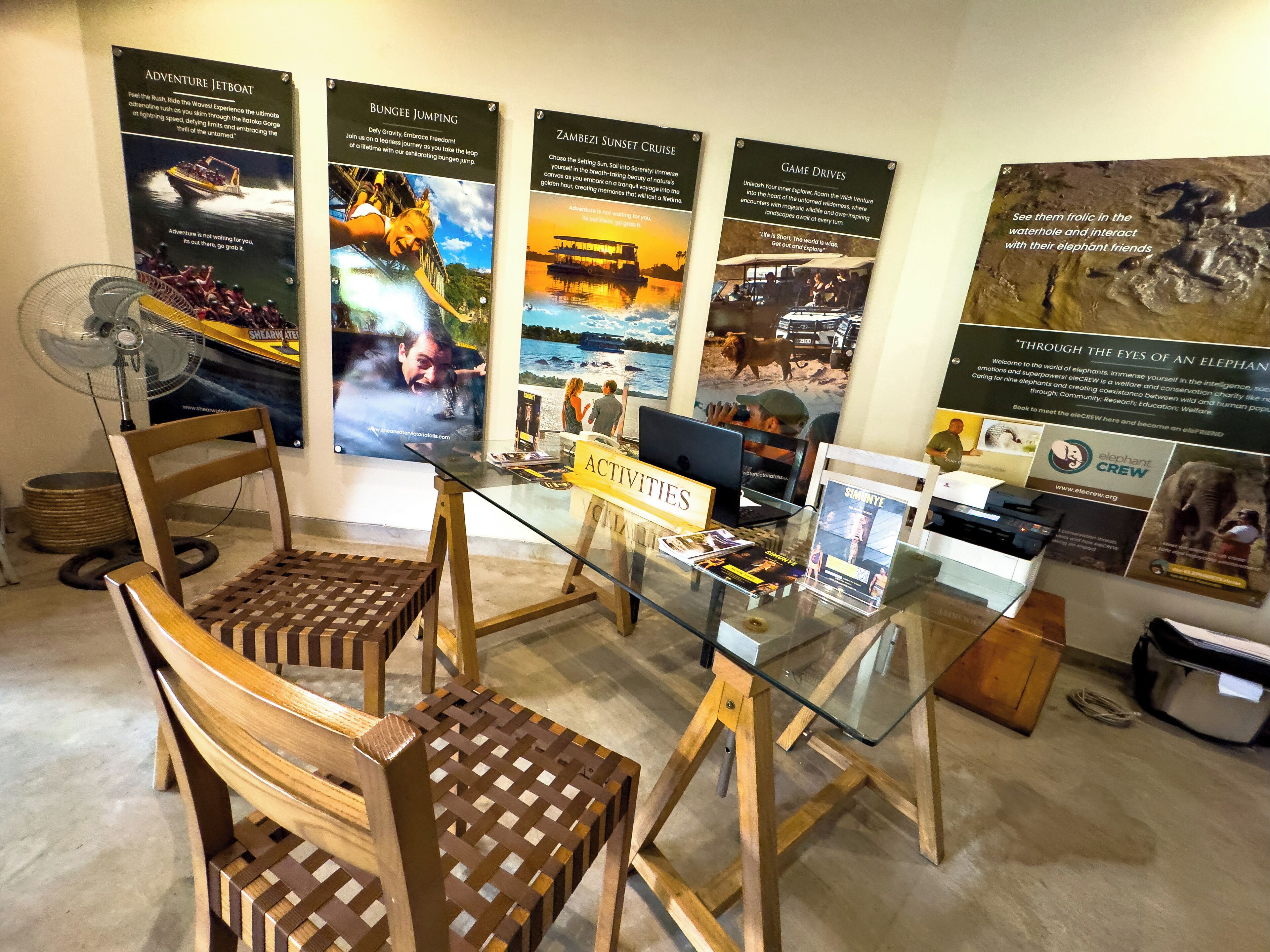 A reception area with a glass table, wooden chairs, and informational posters on the wall.