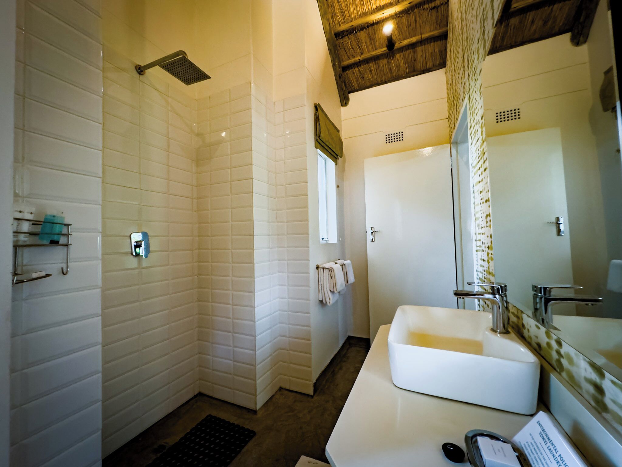 A bathroom with a white sink, a mirror, a shower, and a towel rack.