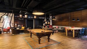 A billiards table in a room with a wooden floor, a sofa, a dining table, and bookshelves. - Pentahotel Hong Kong, Tuen Mun (Tuen Mun)