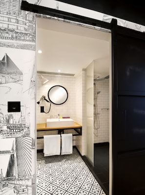 Een moderne badkamer met een wit wastafelmeubel, spiegel en vloer van zwart tegels.