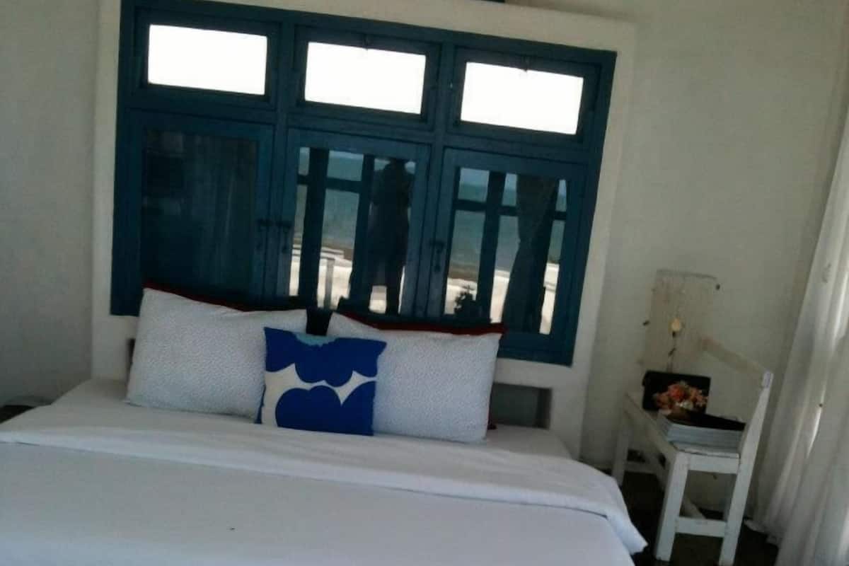 A bedroom with a bed, a nightstand, and a window with blue shutters.