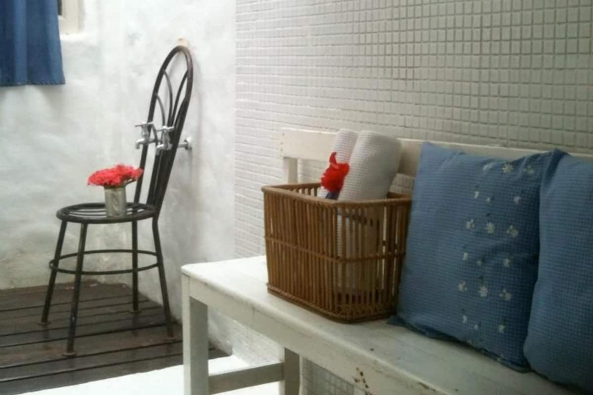 A small, clean room with a white bench, a wicker basket, and a chair with red flowers.