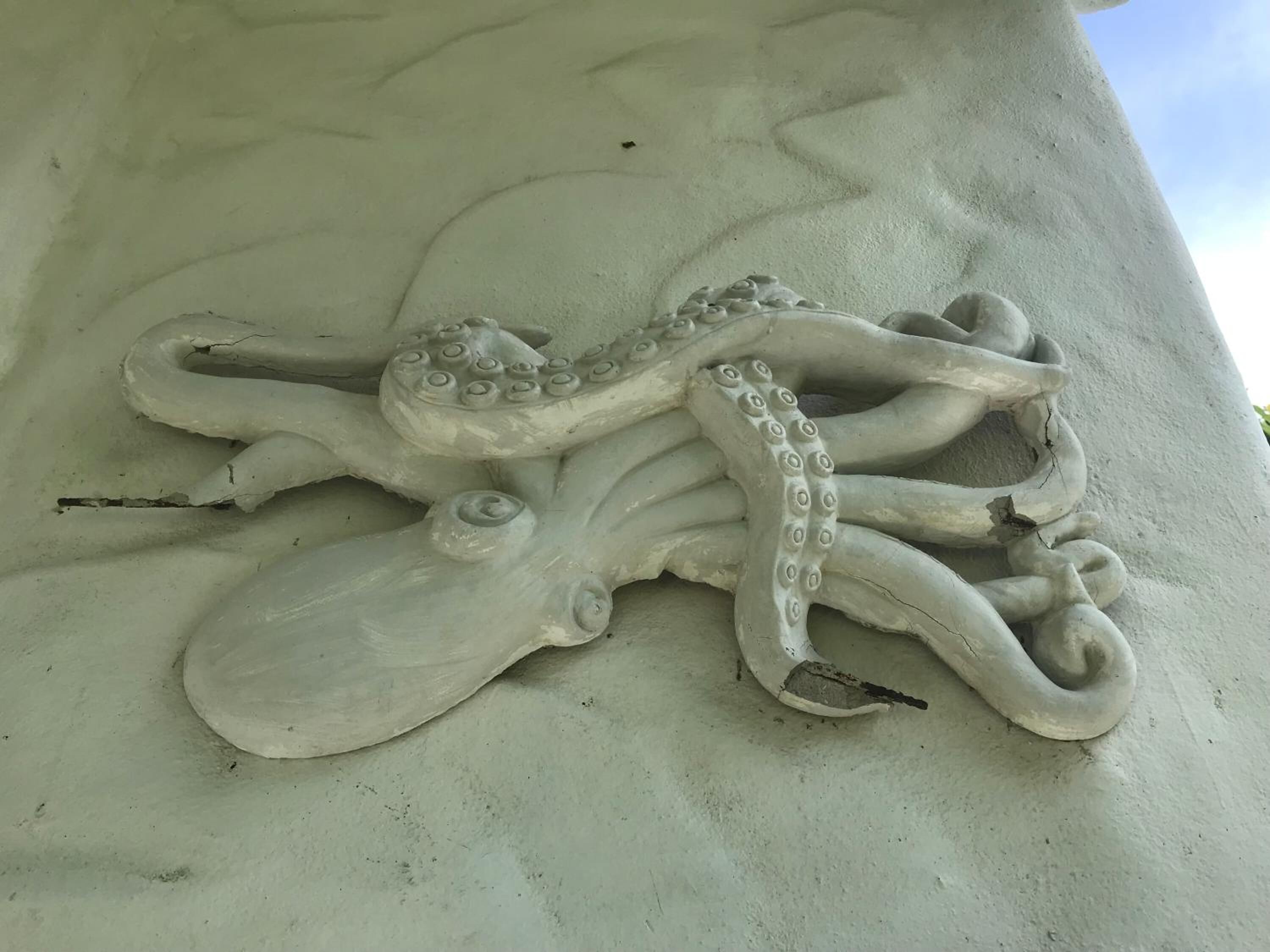 Eine Skulptur eines Oktopus auf einem Betonpfeiler.